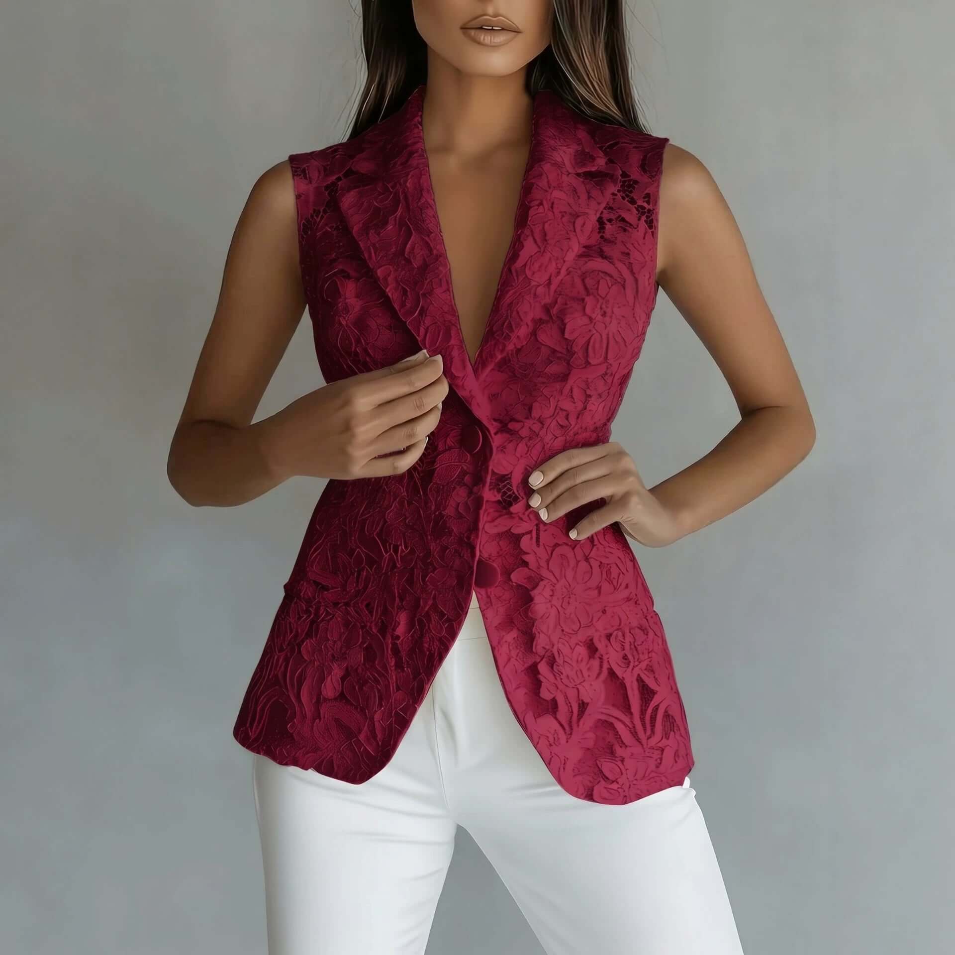 A woman wearing a sleeveless deep burgundy lace vest over a black top and white pants, standing against a neutral gray background.