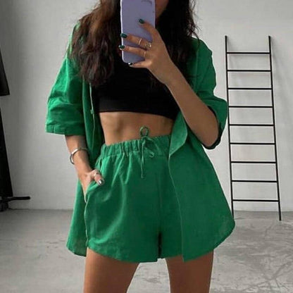 woman wearing a green outfit with shorts and a jacket, standing in a room with a ladder.