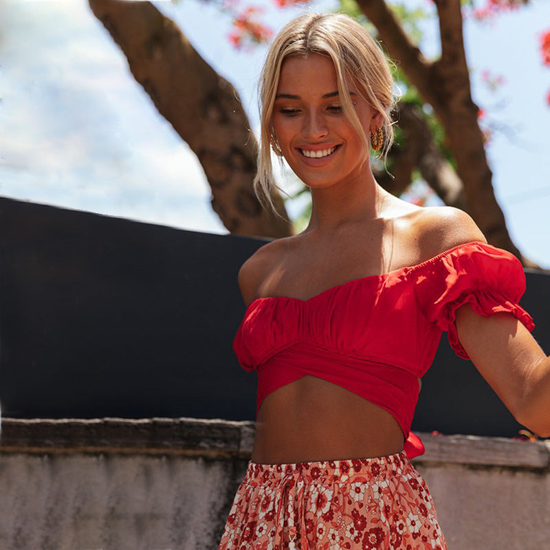 Woman wearing a red off-shoulder top and floral skirt outdoors.