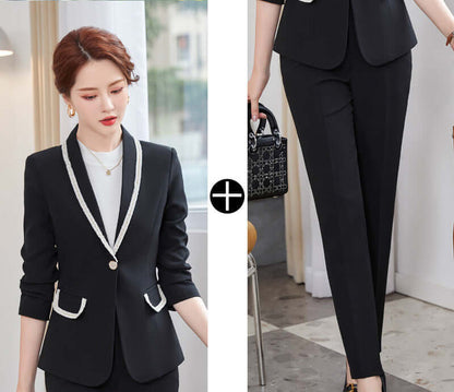 Woman wearing a black suit with white accents, holding a handbag indoors.