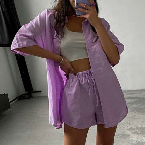Woman wearing a light purple outfit with a matching shirt and shorts, standing indoors.