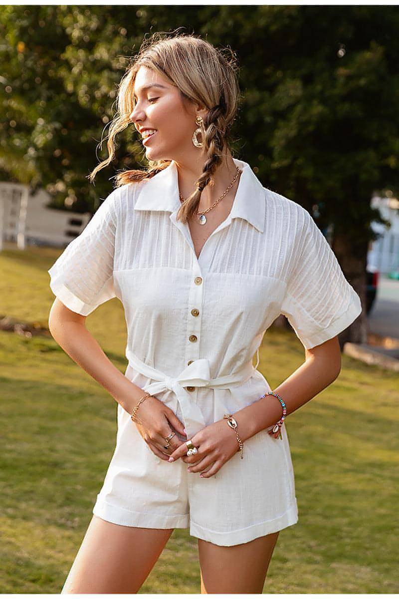 Woman wearing a white outfit with buttons in an outdoor setting