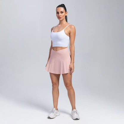 Woman wearing a white tank top and pink skirt on a gray background